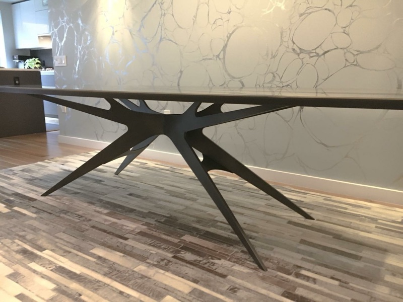 Detail of the blackened-steel sculptural starburst base of a custom brass-and-resin dining table by Van Aken Design