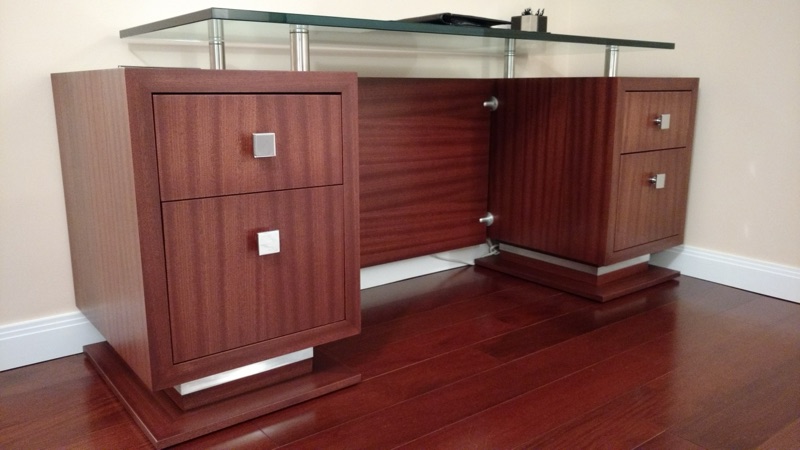 Mahogany-toned home office desk with brushed-steel hardware and a recessed plinth base, custom built by Van Aken Design