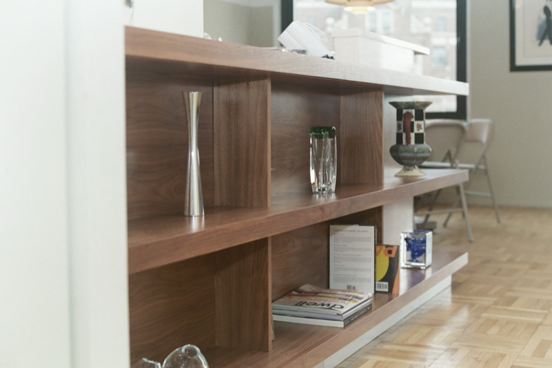 Custom walnut credenza and open shelving styled with vases and books in a sunlit room, by Van Aken Design