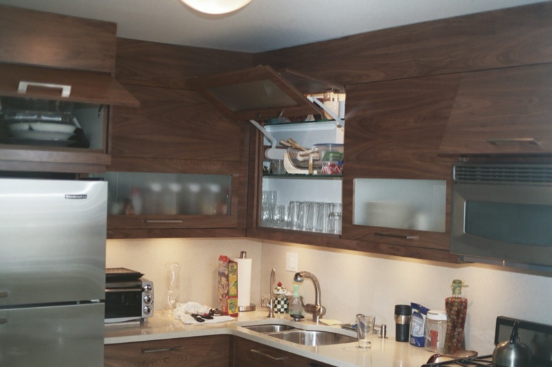 Modern walnut kitchen cabinetry with frosted-glass upper doors and integrated lighting, custom built by Van Aken Design