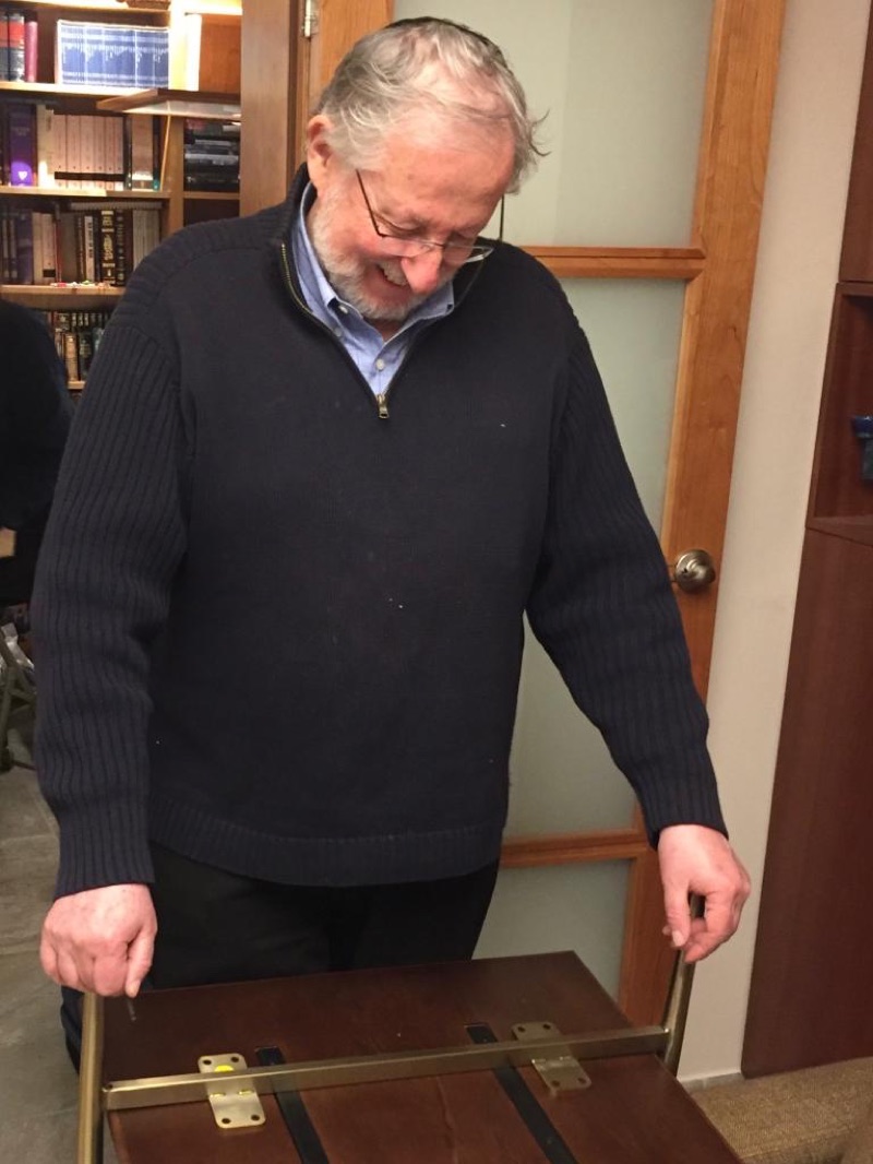 Shlomo David Offer, owner, designer and builder at Van Aken Design, examining a custom wooden table with brass hinges in his workshop