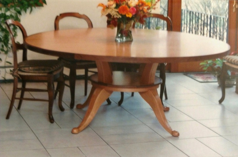 Traditional round hardwood dining table on a turned pedestal with carved scrolled feet, custom built by Van Aken Design
