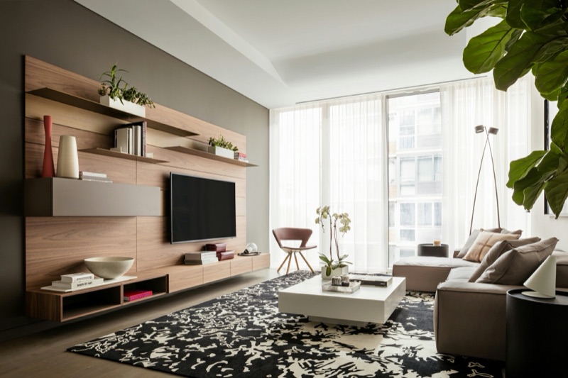 Floating oak wall-mounted media unit with cantilevered shelves framing a television in a modern living room, by Van Aken Design